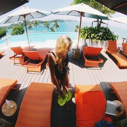 High angle view of woman standing amidst lounge chair at poolside