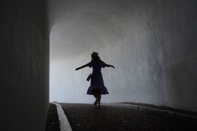 Rear view of woman walking on street in tunnel