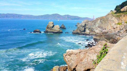 Scenic view of rugged sea coastline golden gate bridge and mountains against sky