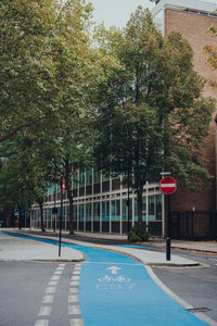 Road sign by trees on street in city