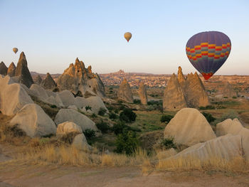 Hot air balloon flying over rocks against sky