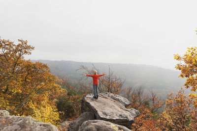 Germany, rhineland palatinate, palatinate forest, woman practising yoga on drachenfels in autumn