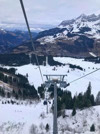 Overhead cable car on snowcapped mountains against sky