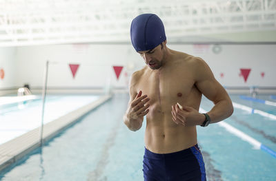 Rear view of shirtless man standing in swimming pool