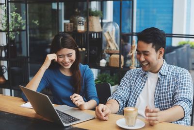 Young man using smart phone while sitting on table