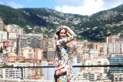 Portrait of smiling woman standing against cityscape