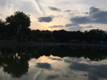 Reflection of trees in calm lake at sunset