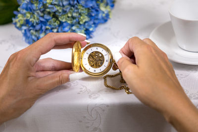 Close-up of woman holding pocket watch on table