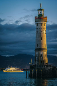 Illuminated tower by sea against sky