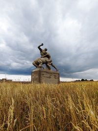Statue on field against sky