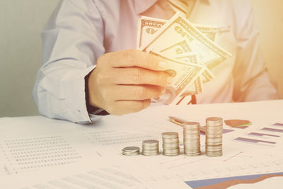 Midsection of businessman holding money at desk in office