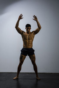 Shirtless muscular man exercising against wall