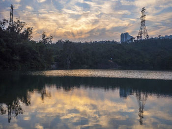 Reflection of trees in lake against cloudy sky