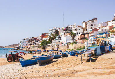 Boats moored on beach against clear sky