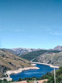 Scenic view of lake and mountains against blue sky