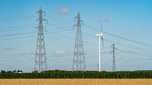 Low angle view of electricity pylon on field against sky