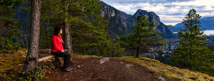 Woman standing on rock by trees on mountain