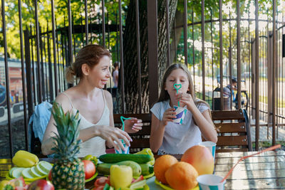 Mother and daughter drinking juice while sitting at restaurant