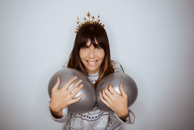 Portrait of young woman with arms raised against white background