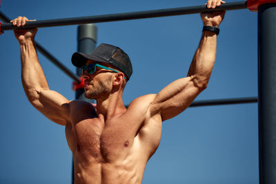 Low angle view of shirtless man exercising in gym