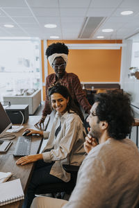 Smiling businesswoman discussing strategy with colleagues during meeting in office