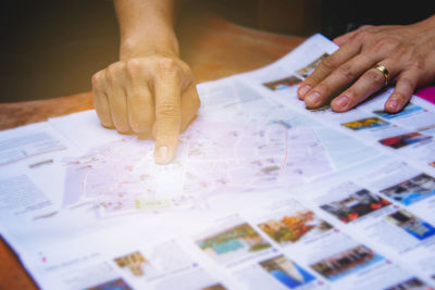 Midsection of person holding paper with text on table