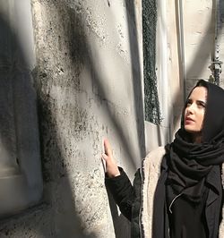 Portrait of woman standing by window at home