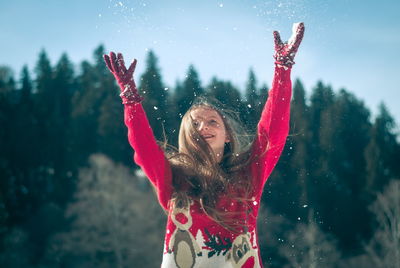 Portrait of young woman with arms outstretched in snow