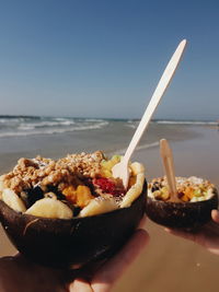 Close-up of ice cream in bowl at beach against sky