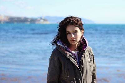 Portrait of smiling young woman standing against sea