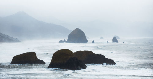 Rock formation in sea against sky