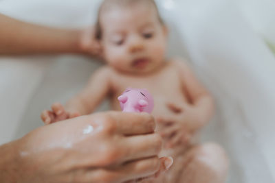 Cropped hands bathing baby girl in bathtub at home