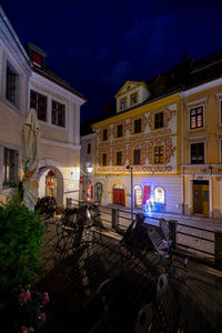 Illuminated building by street against sky at night