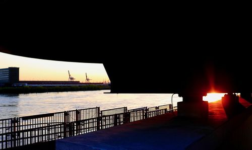 Silhouette building by sea against clear sky during sunset