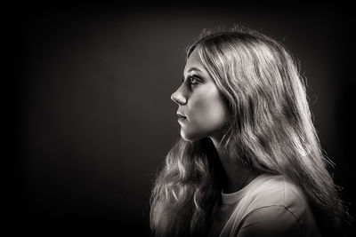 Side view of young woman against black background