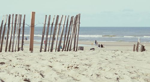 Panoramic view of wooden posts on beach against sky