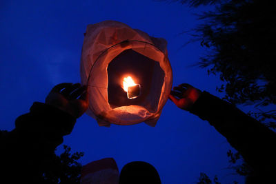 Low angle view of hand holding illuminated against clear blue sky