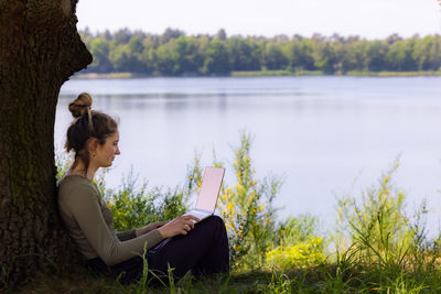 Side view of woman sitting by lake