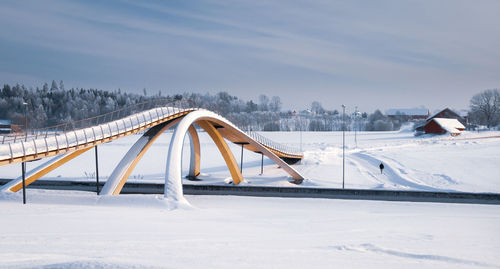 Snow covered bridge on field against sky