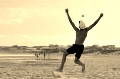Full length of man on beach against sky during sunset