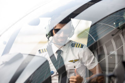 Portrait of pilot gesturing while sitting at cockpit