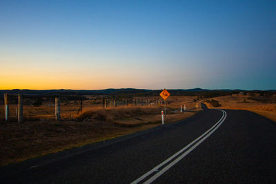 Empty road against clear sky during sunset