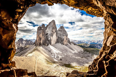 Scenic view of rock formations and mountains seen through hole against sky