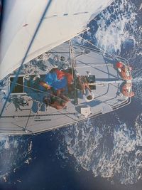 Reflection of people on sailboat in sea