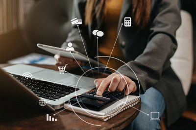 Midsection of man using mobile phone while sitting on table