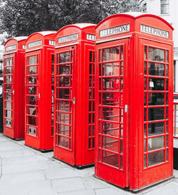 Red telephone booth on sidewalk in city