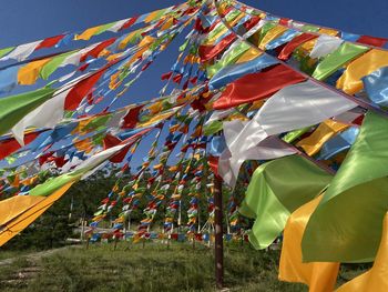 Multi colored flags hanging on field against sky