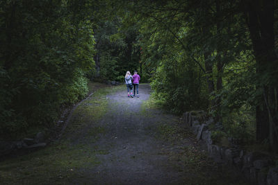 Rear view of women walking on footpath in forest