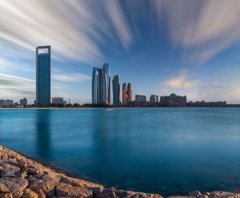 Sea by city buildings against sky