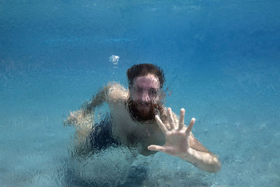 Man swims in glass pool on vacation